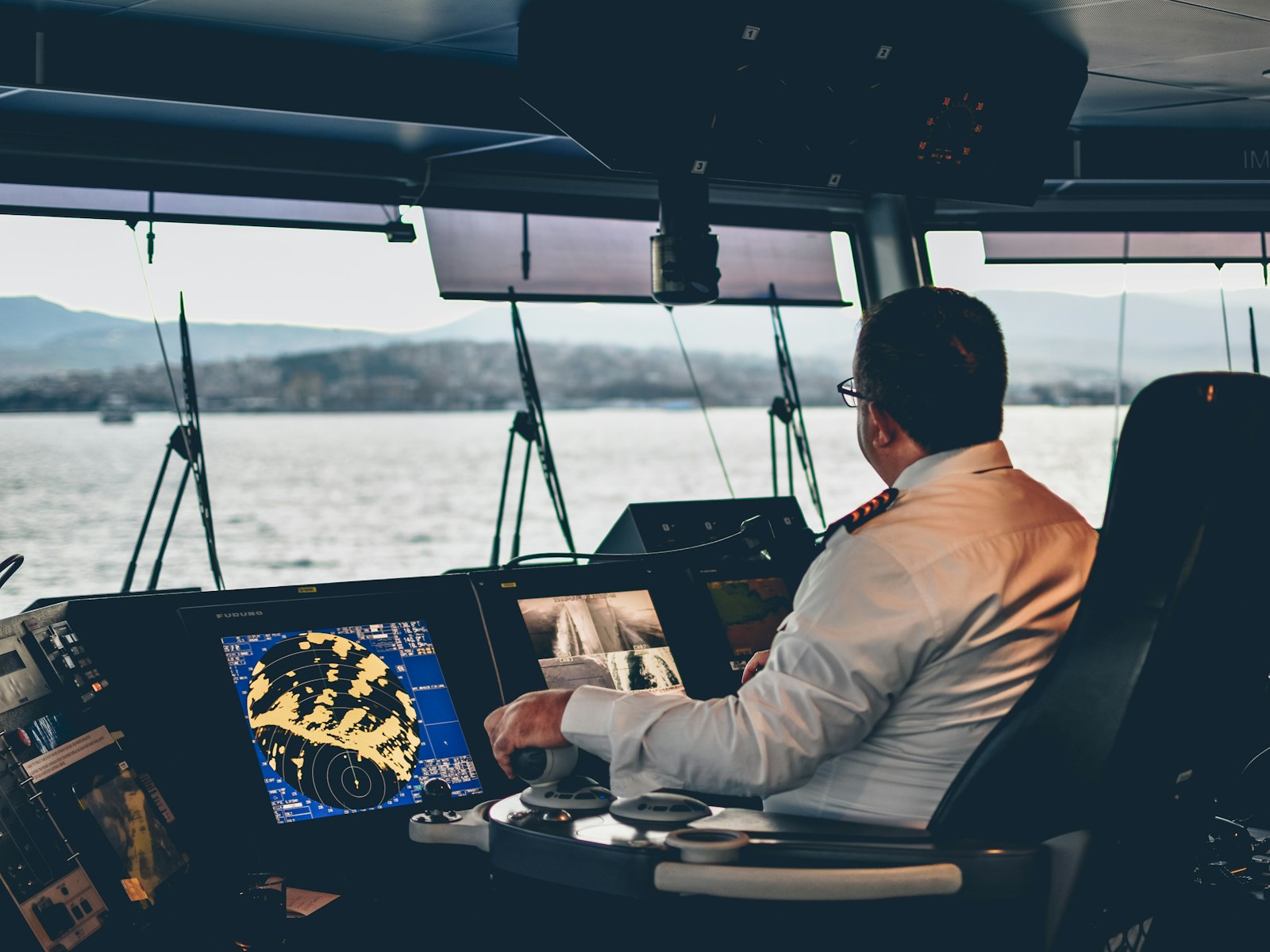 Un capitaine à la passerelle d'un grand yacht, devant les écrans de navigation