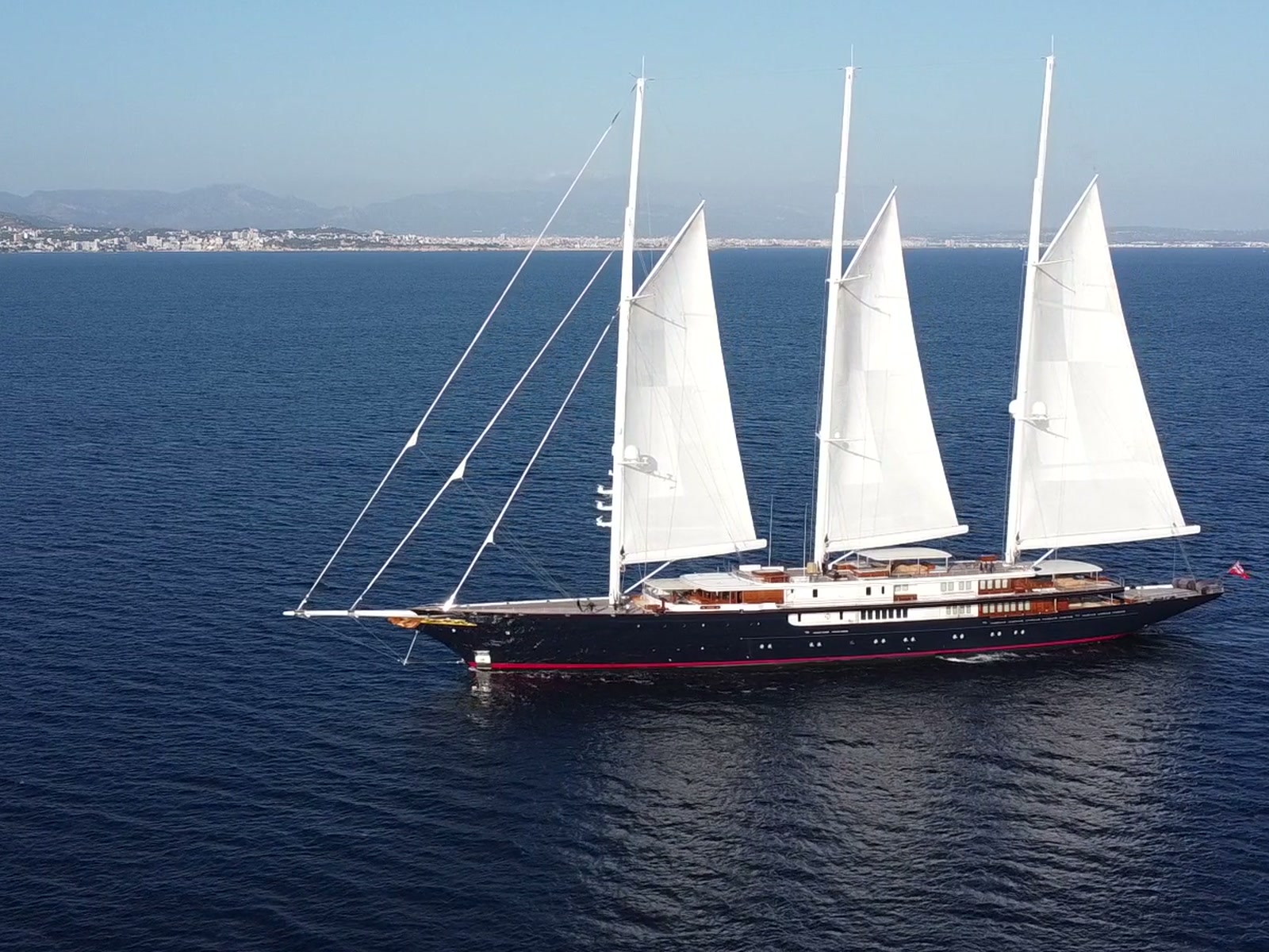 Une grande goélette à trois mâts sous voiles, au large de la côte