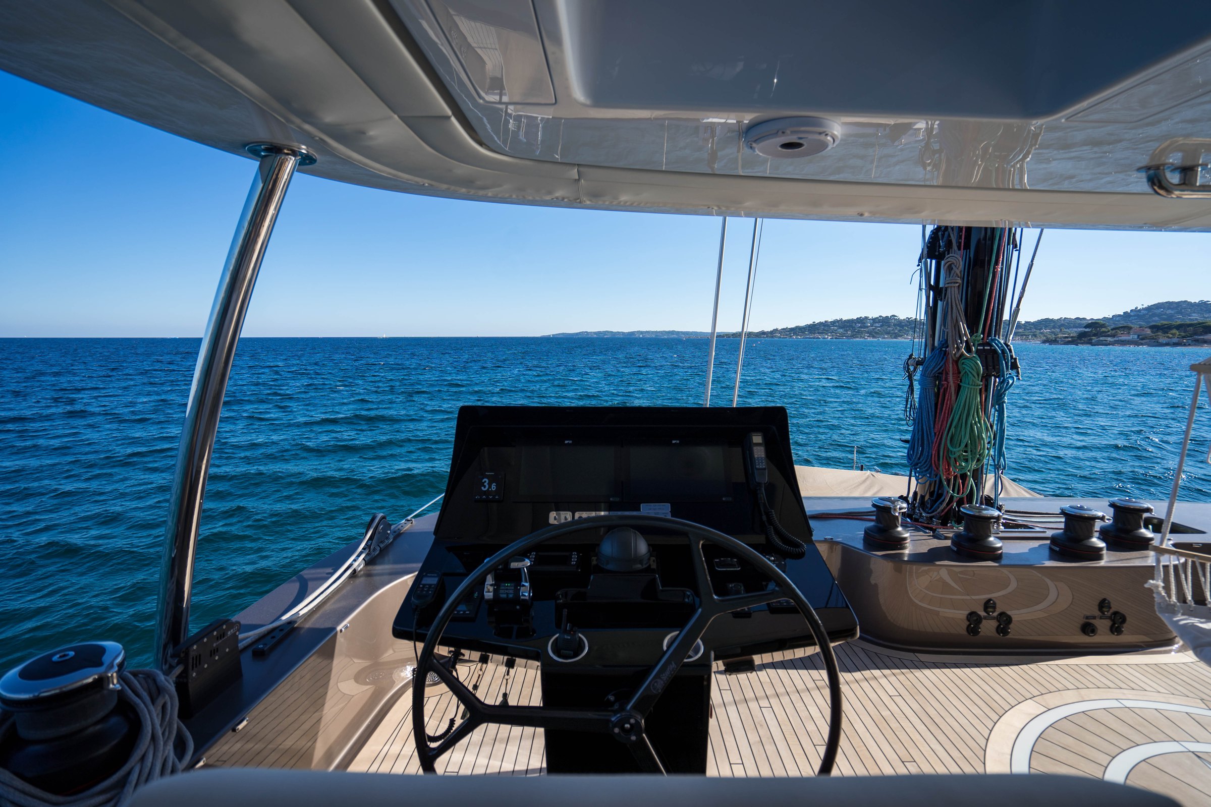 The flybridge helm station on Āura, wheel facing the open sea