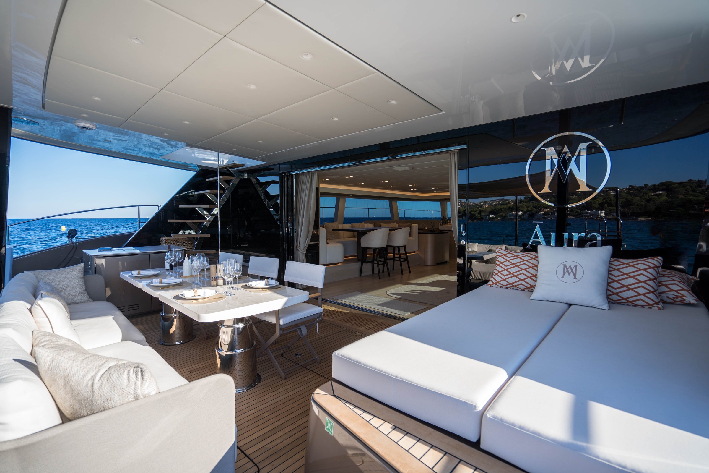 The aft cockpit of Āura, sunpad, dining table and monogrammed cushions